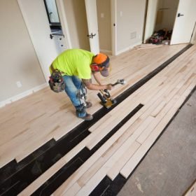 A workman innstalling a maple hardwood floor in a residential home construction.